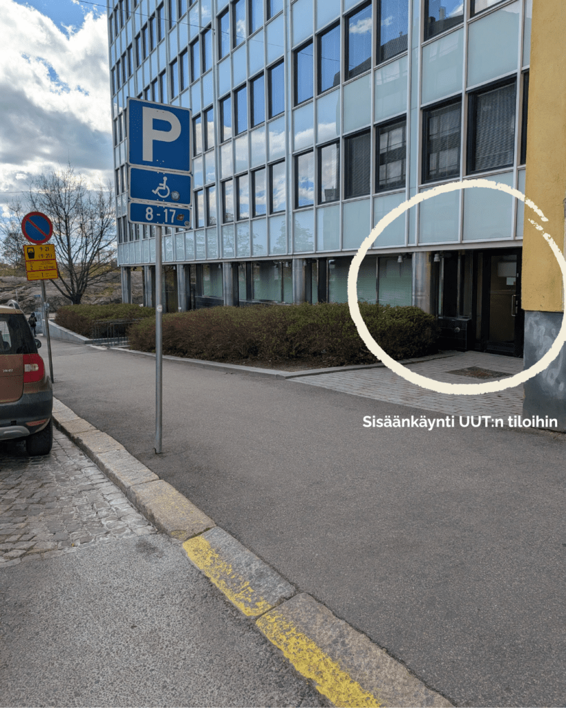 Toimistorakennuksen julkisivu kadulta kuvattuna. Kuvassa pysäköintimerkki ja kadun varteen parkkeerattu auto. Kuvan oikeassa laidassa ympyrällä merkitty sisäänkäynti rakennuksen ovelle.